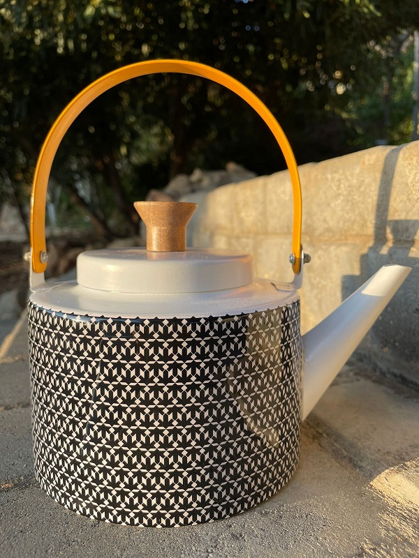 alt="black tea pot with designs"