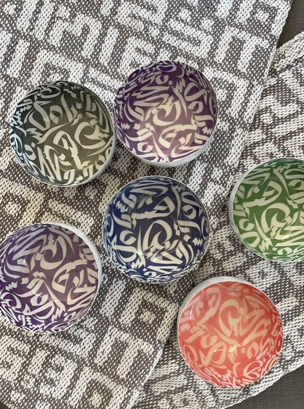 alt="colourful metal bowls with arabic calligraphy design"