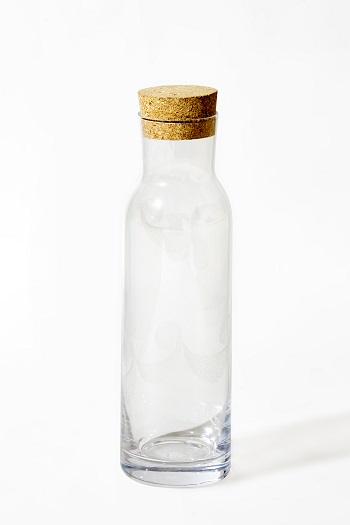 Glass jug with a cork lid, adorned with white Arabic alphabets designed in an array of dots.
