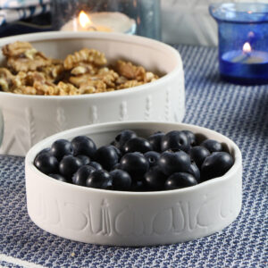 Nuzha bowl of blueberries and nuts sitting on a wooden table. 